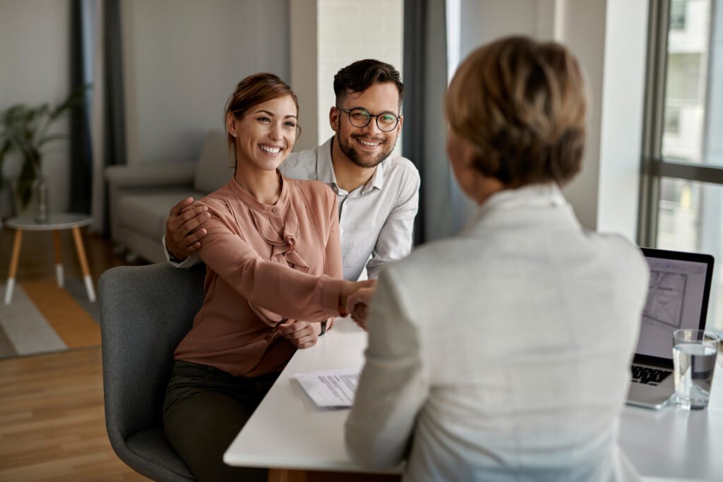 Happy couple greeting their real estate agent in the office.